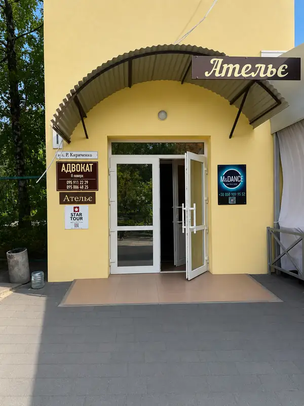 Жовтий будинок з аркою над входом і вивіскою «Ательє»